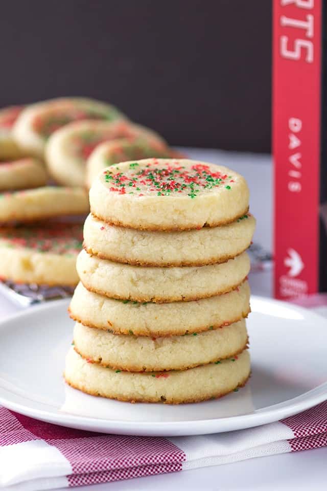 A stack of Laughing Cow sugar cookies with sprinkles on a plate.