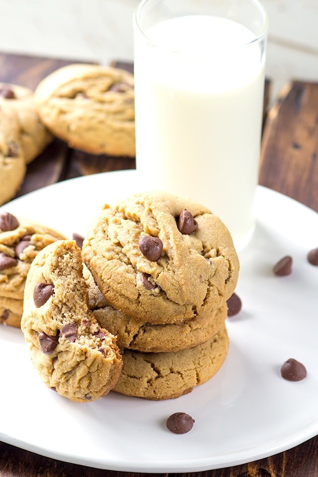 white plate with a stack of peanut butter chocolate chip cookies. One cookie has a bite taken out of it