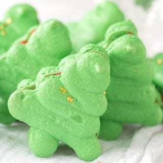 Green macarons shaped like Christmas trees displayed on a white table.