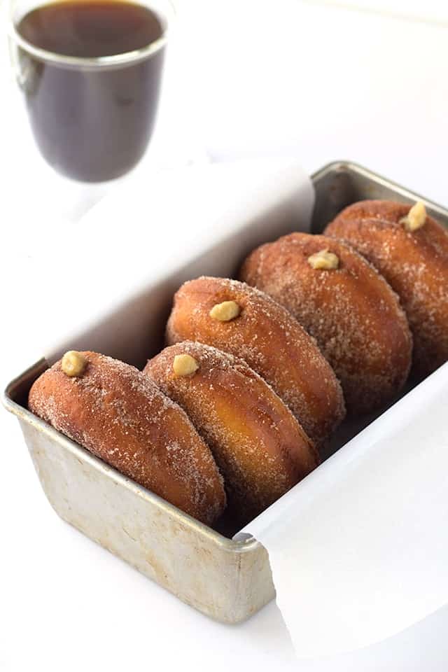 Cinnamon sugar donuts in a pan with a cup of coffee.