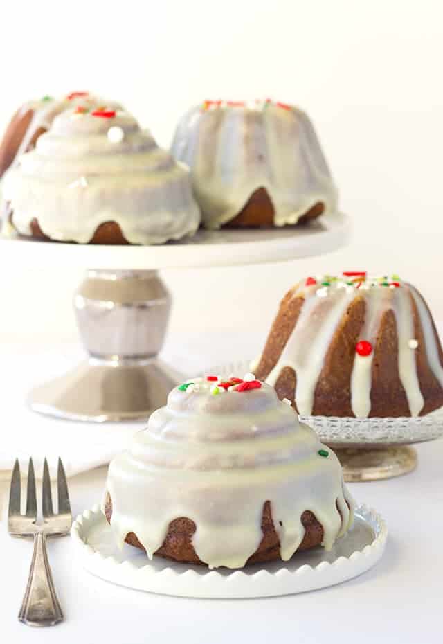 Three gingerbread bundt cakes with icing and sprinkles on top.