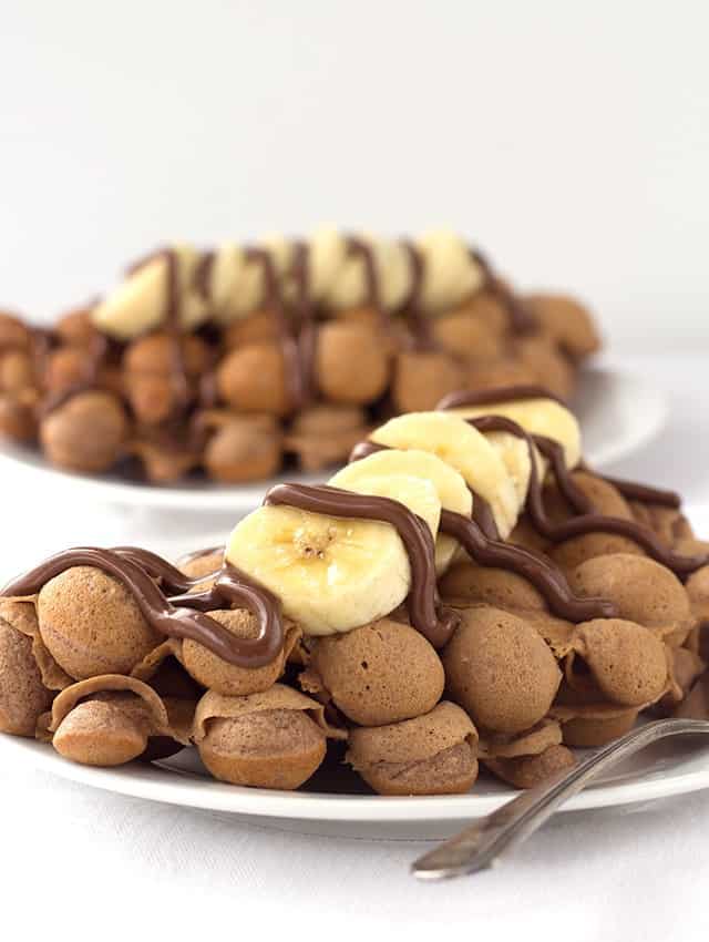 A plate of Nutella bubble waffles topped with bananas.