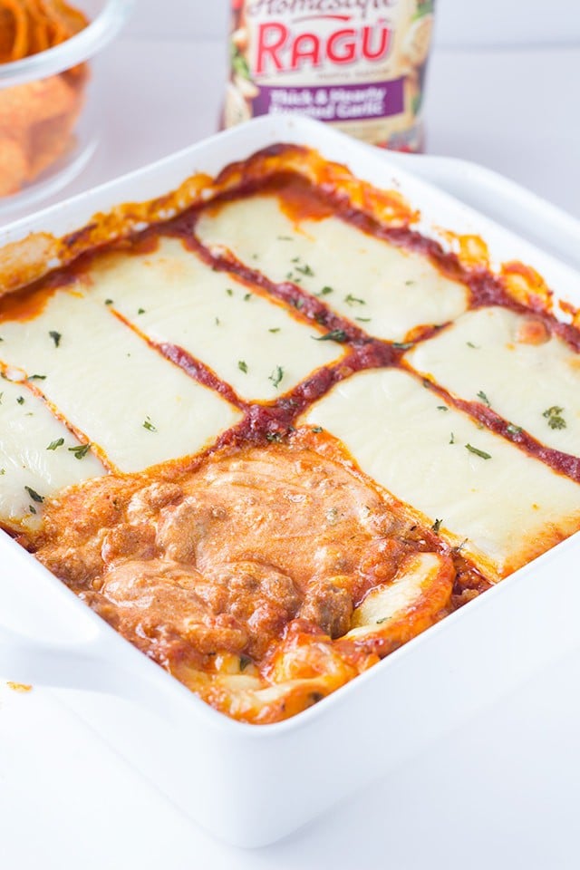 This lasagna dip recipe is a must make party dip. It's a hearty dip with 3 kinds of cheese and sausage and can be served with toasted baguette slices or chips! warm lasagna dip covered in slices of mozzarella cheese