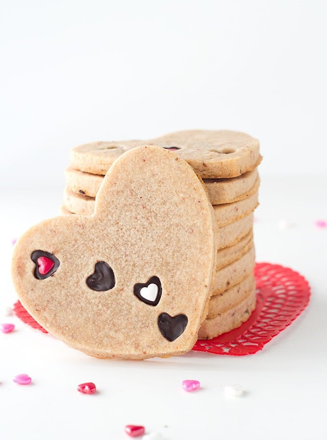 Strawberry Sugar Cookies - Delicious cut-out strawberry flavored sugar cookies with little heart cut outs that are filled with milk chocolate. The perfect Valentine's Day treat!