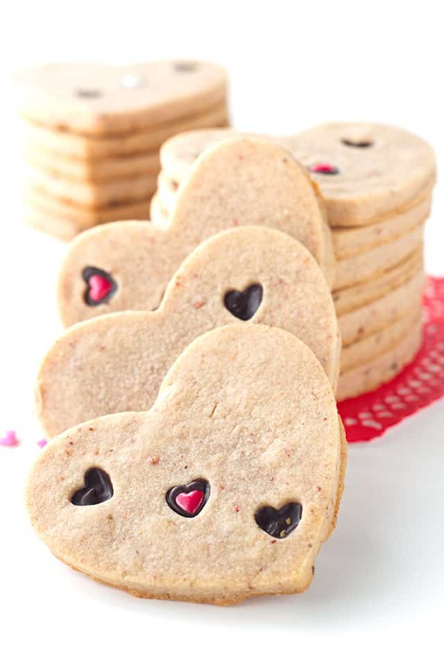 Strawberry Sugar Cookies - Delicious cut-out strawberry flavored sugar cookies with little heart cut outs that are filled with milk chocolate. The perfect Valentine's Day treat!