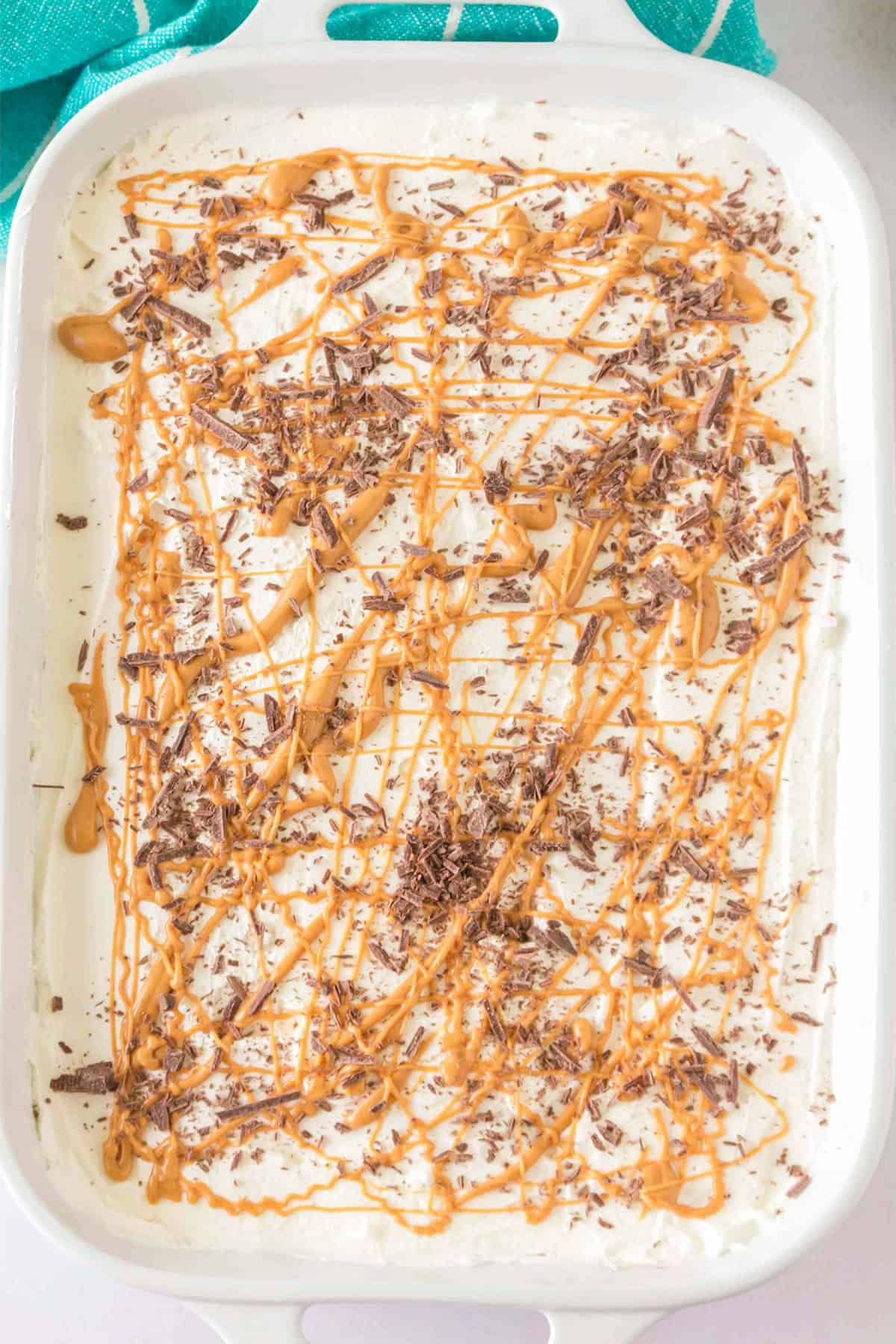 A rectangular dish filled with Chocolate Peanut Butter Layer Dessert, topped with drizzled caramel and chocolate shavings.