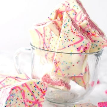 Frosted Animal Cracker Bark - A white chocolate shell with a cream cheese frosted animal cracker filling sandwiched between it. Finish the bark with a pink chocolate drizzle and colorful sprinkles. This fun bark is the perfect dessert to give as a gift.