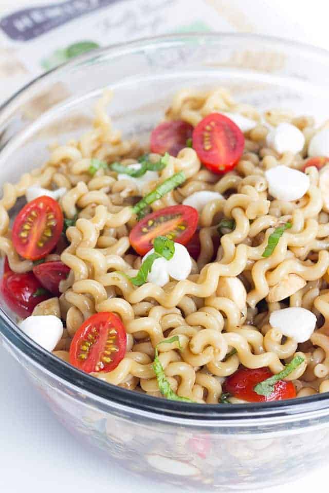 Big glass bowl full of Caprese Pasta Salad