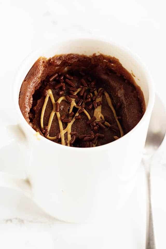chocolate sprinkles on a chocolate peanut butter mug cake in a white mug