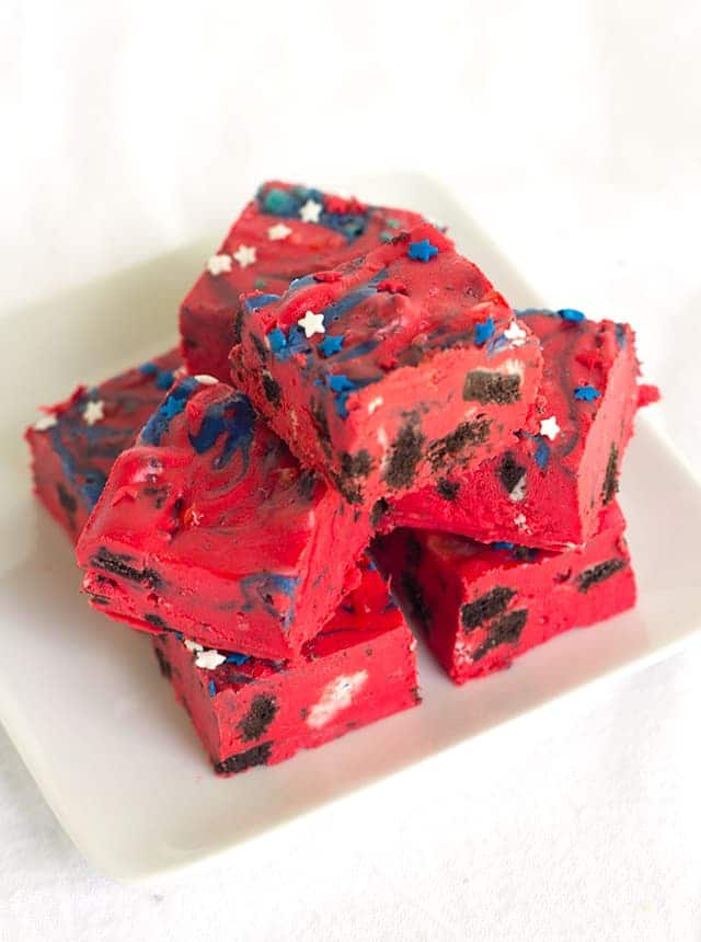 Oreo Frosting Fudge - easy fudge made with white chocolate chips, red store-bought frosting, and stuffed with popping oreos and star sprinkles.