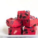 Oreo Frosting Fudge - easy fudge made with white chocolate chips, red store-bought frosting, and stuffed with popping oreos and star sprinkles.