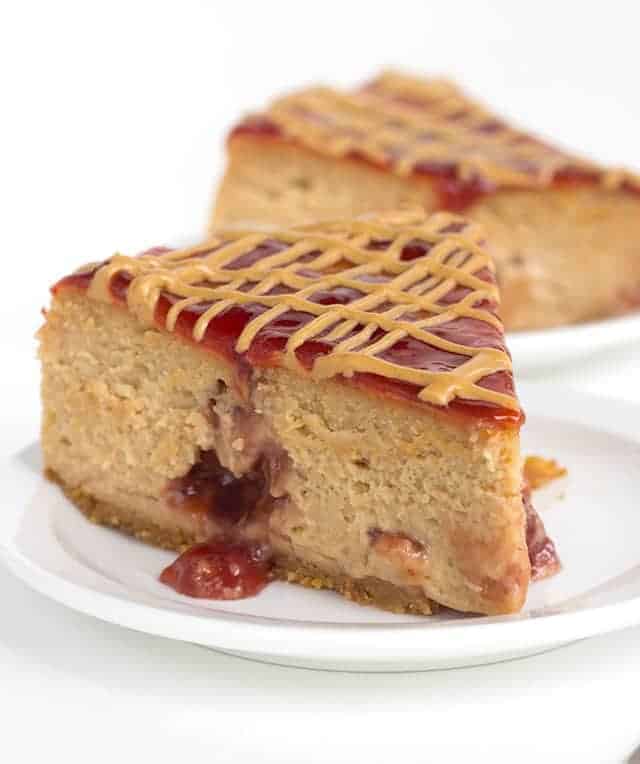 slice of peanut butter and jelly cheesecake on a white plate with jelly pouring out