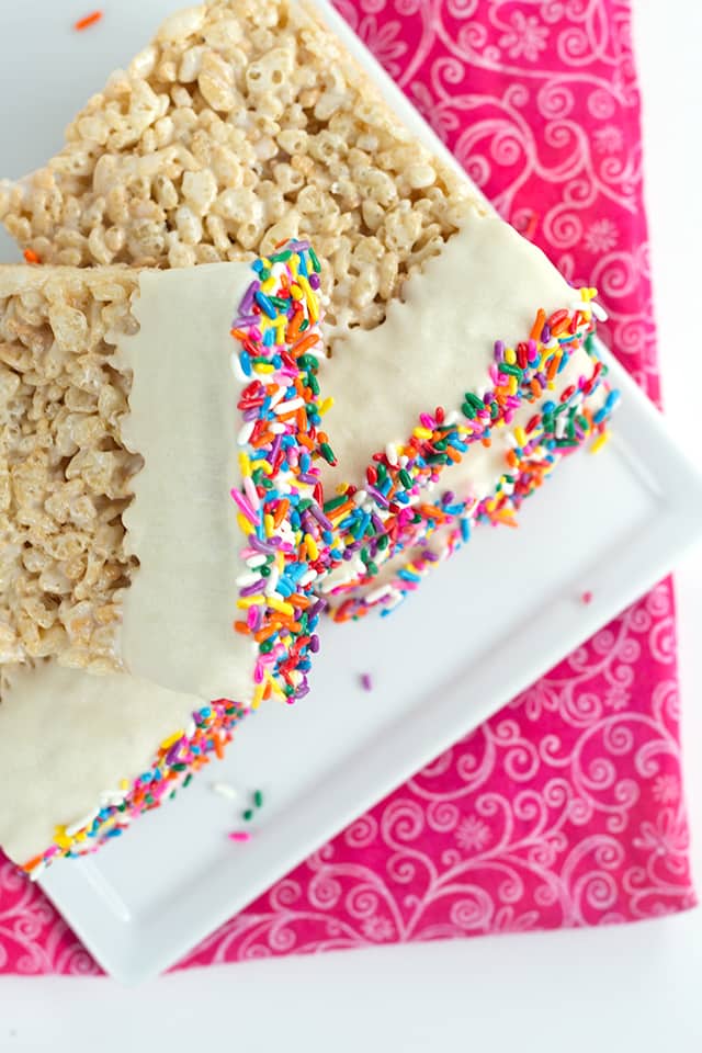 Chocolate Dipped Rice Krispie Treats - classic rice krispie treats dipped in chocolate and the ends are coated in loads of colorful sprinkles! They're a huge hit at any bake sale! #dessertfoodrecipes #cookiedoughandovenmitt #sprinkles #ricekrispietreats #dessertrecipes overhead of chocolate dipped rice krispie treats showing sprinkles