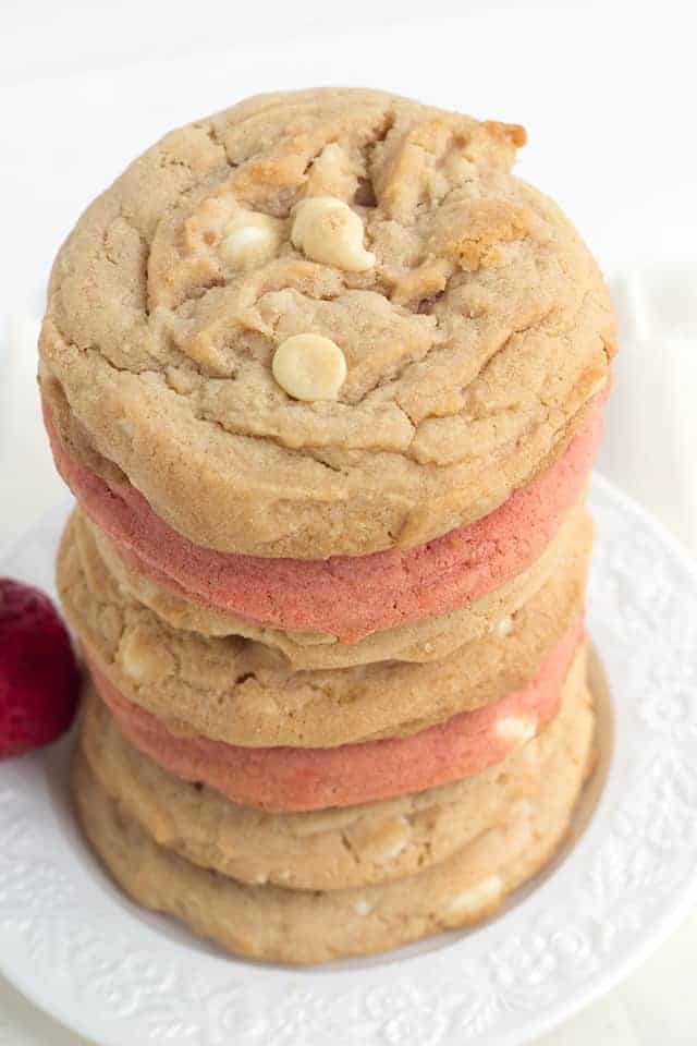 A stack of strawberry cheesecake cookies on a white plate with strawberry