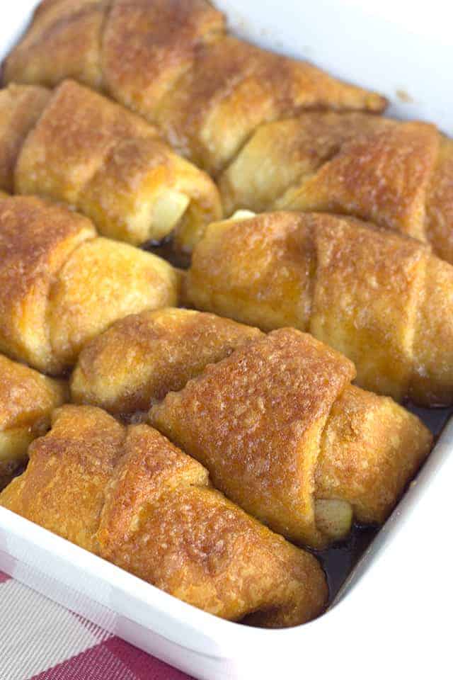 Crescent Roll Apple Dumplings - slices of apples rolled up in crescent rolls with cinnamon and sugar. Once everything is in the pan, it's coated with a layer of a buttery cinnamon brown sugar mixture and baked.