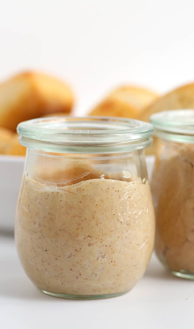 Two jars of sweet peanut butter on a white table.