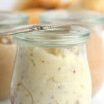 A jar Maple Pecan Butter on a white surface with two other jars of compound butters behind it