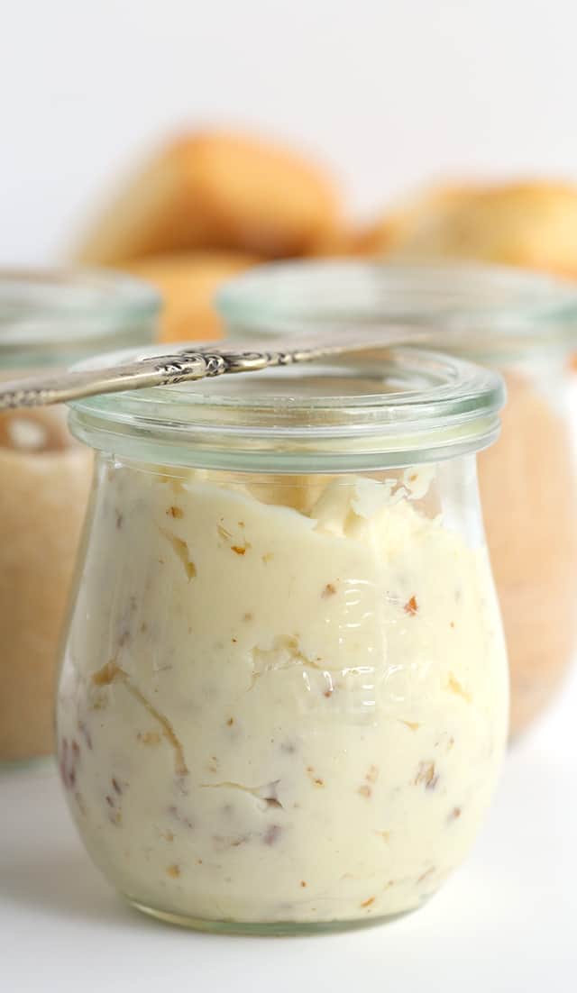 A jar Maple Pecan Butter on a white surface with two other jars of compound butters behind it