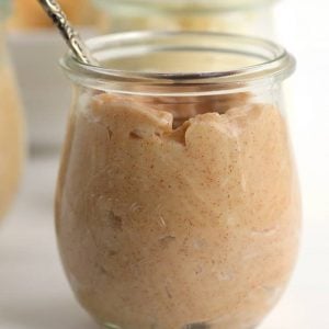 Peanut butter in a glass jar with a spoon, now infused with cinnamon and sugar.