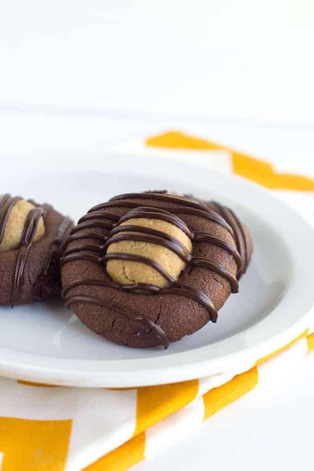 close up thumbprint cookie propped up on a white dessert plate with a yellow chevron linen