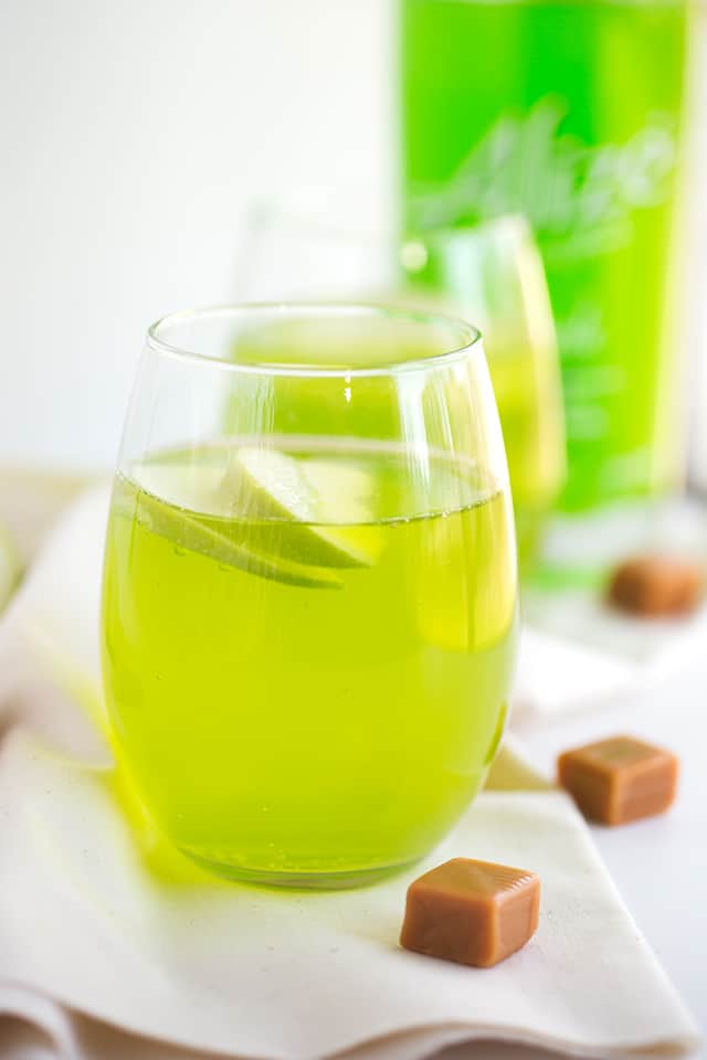 caramel apple cocktail on a white fabric with caramels