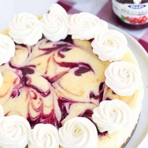 A cranberry cheesecake with whipped cream and cranberries.