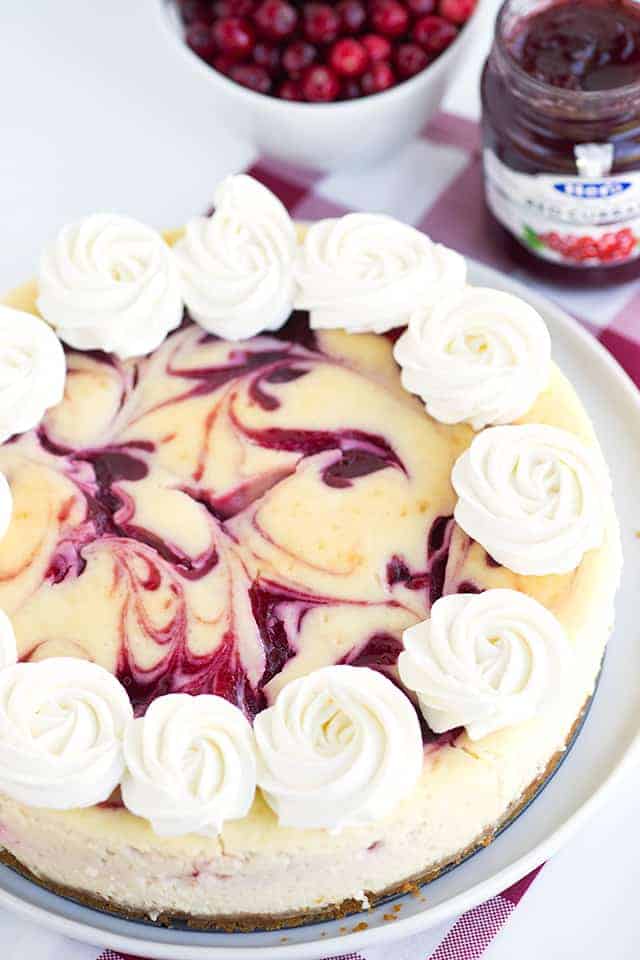 A cranberry cheesecake with whipped cream and cranberries.