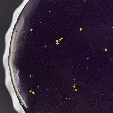 A Mirror Glaze Cake decorated with purple and gold stars.