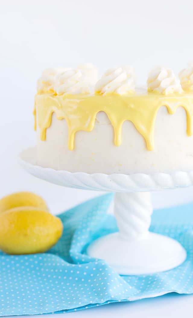 yellow colored white chocolate ganache dripping down the sides of a 2-layer olive oil cake