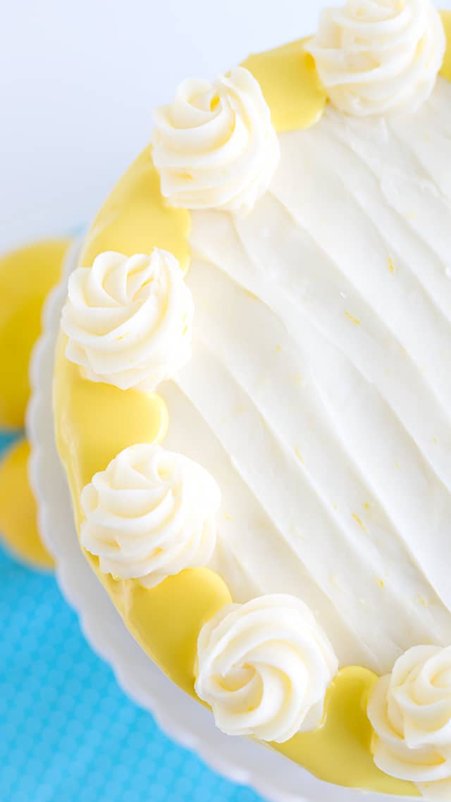 looking down onto the top of a lemon olive oil cake with swirls of cream cheese frosting on top