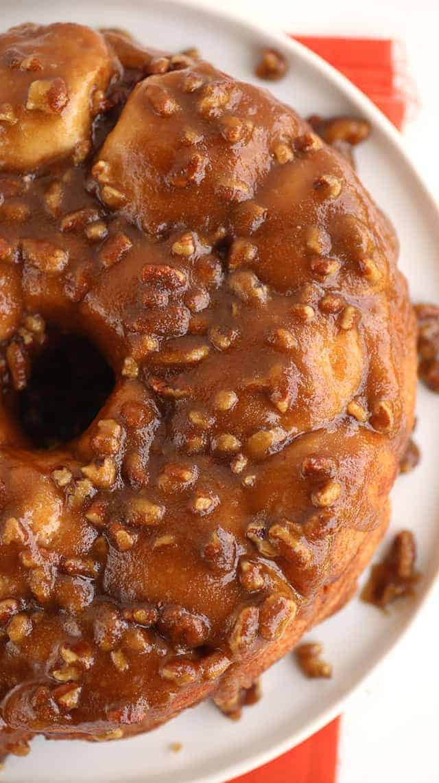 A Pecan Pie bundt cake with caramel and pecans on a plate.
