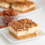 Pecan cheesecake bars on a white plate.