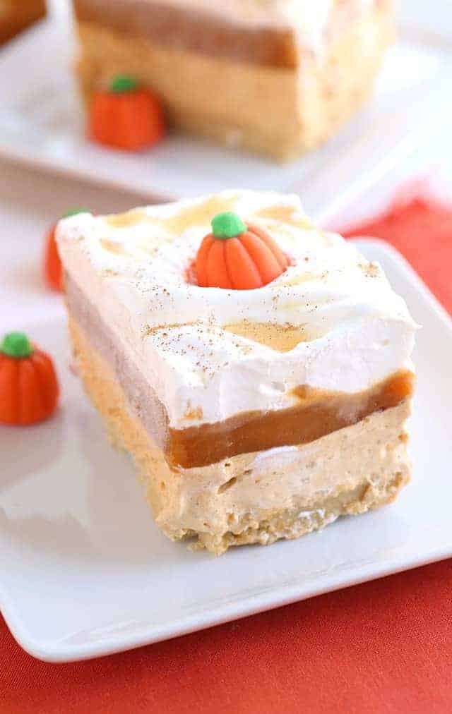 Pumpkin Butterscotch Layer Dessert - Layers of crushed vanilla sandwich cookies, pumpkin cheesecake, butterscotch pudding, whipped topping, and adorable candy pumpkins! This screams the perfect Fall and Thanksgiving dessert! It's so simple to make too!