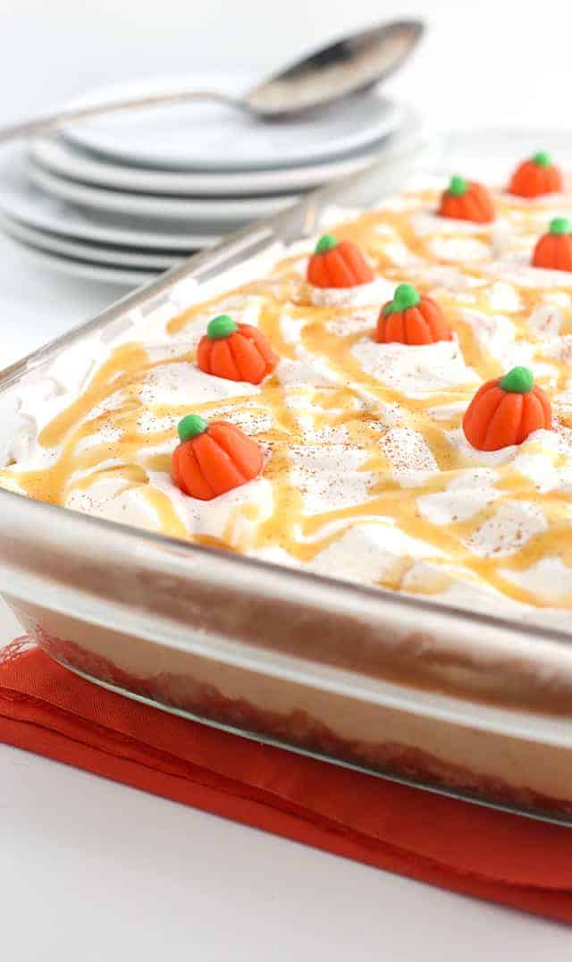 Pumpkin Butterscotch Layer Dessert - Layers of crushed vanilla sandwich cookies, pumpkin cheesecake, butterscotch pudding, whipped topping, and adorable candy pumpkins! This screams the perfect Fall and Thanksgiving dessert! It's so simple to make too!