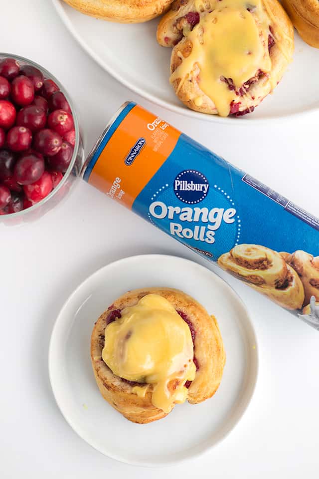 Showing cranberry orange cinnamon rolls from above with a package of store-brought orange rolls 