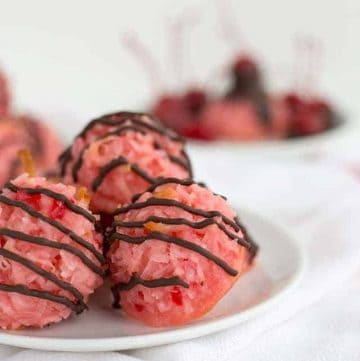 A plate of pink cherry doughnuts with coconut macaroon toppings.