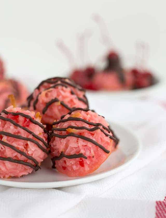 A plate of pink cherry doughnuts with coconut macaroons on top.