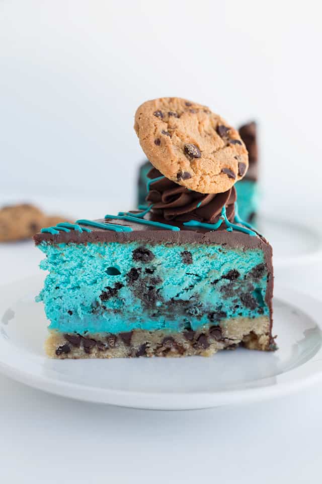 side shot of a slice of the cookie monster cheesecake on a white plate