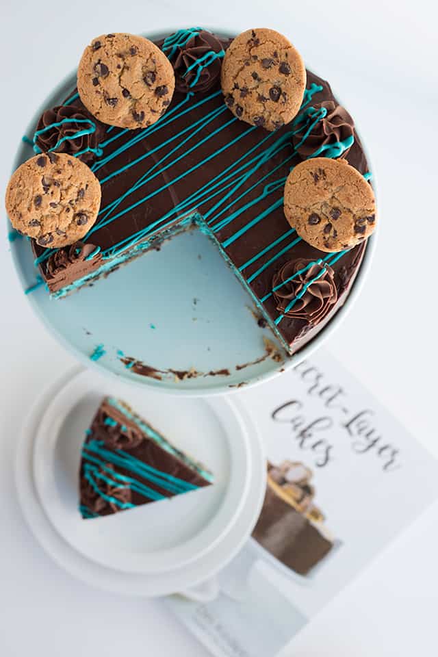overhead shot of the cookie monster cheesecake with a slice sitting below the cheesecake on a cookbook