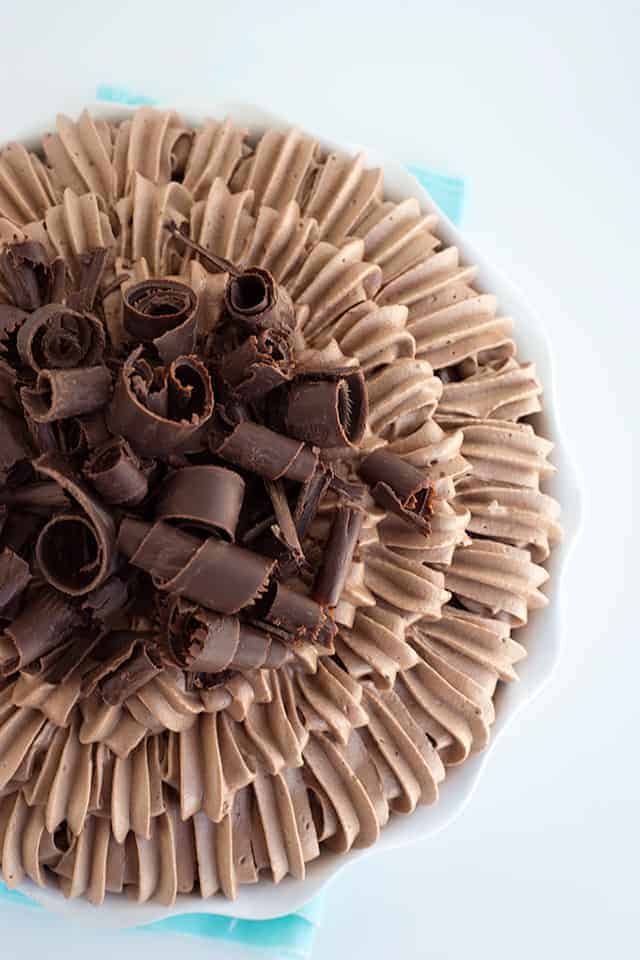 overhead shot of a chocolate cream pie in a white pie plate with the chocolate whipped cream piped on to and large chocolate curls.