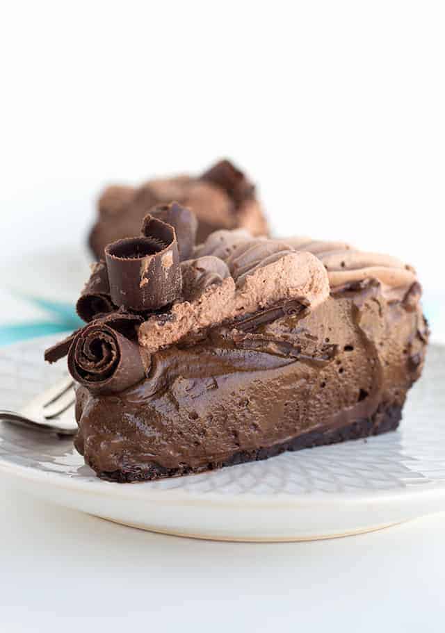 A side shot of a slice of the chocolate cream pie on a white plate.