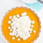 overhead shot of a pichuberry tart in a white tart pan with a stack of white plates.