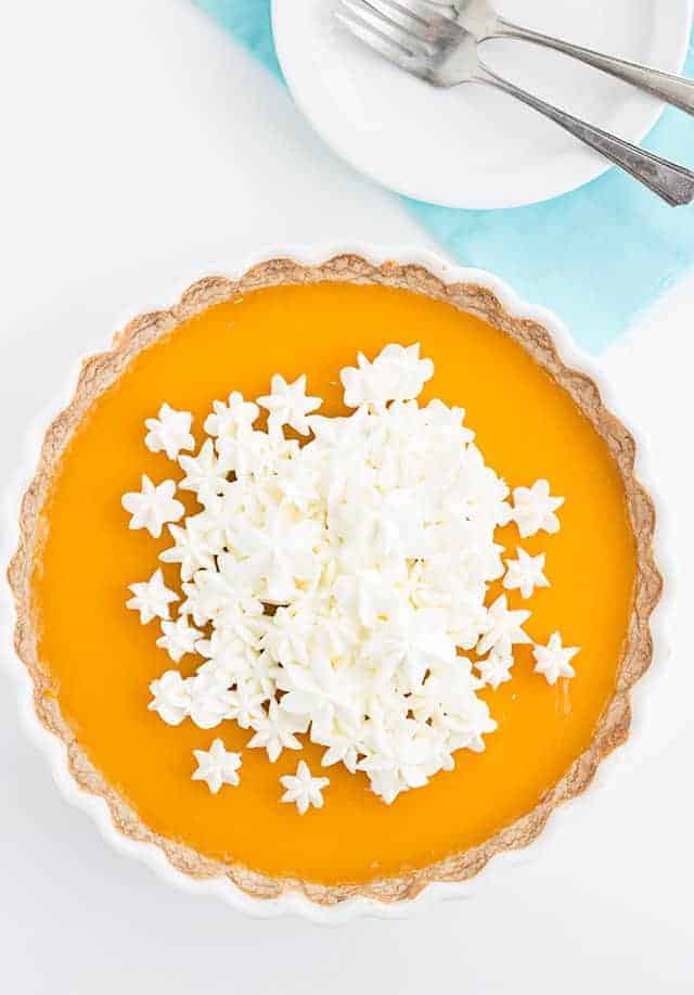 overhead shot of a pichuberry tart in a white tart pan with a stack of white plates.