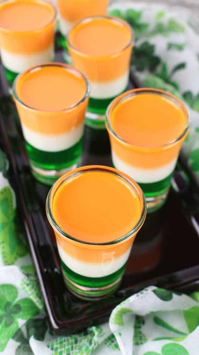 Overhead shot of St. Patrick'sDay Jello Shots on a black plate with a shamrock fabric