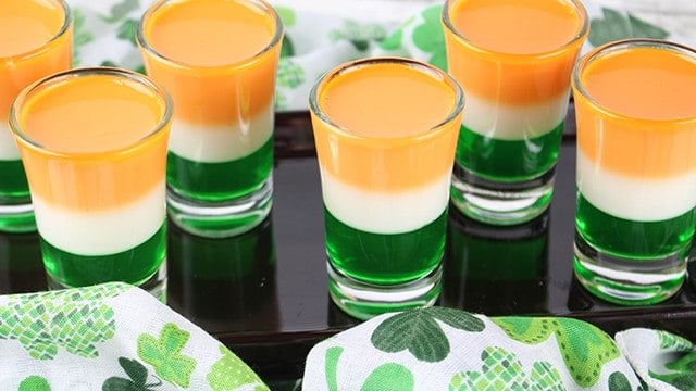 St. Patrick's Day Jello Shots staggered on a black plate with a shamrock fabric 