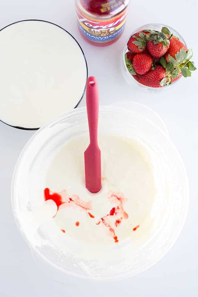 cheesecake batter separated into two bowls, one being flavored with strawberry syrup