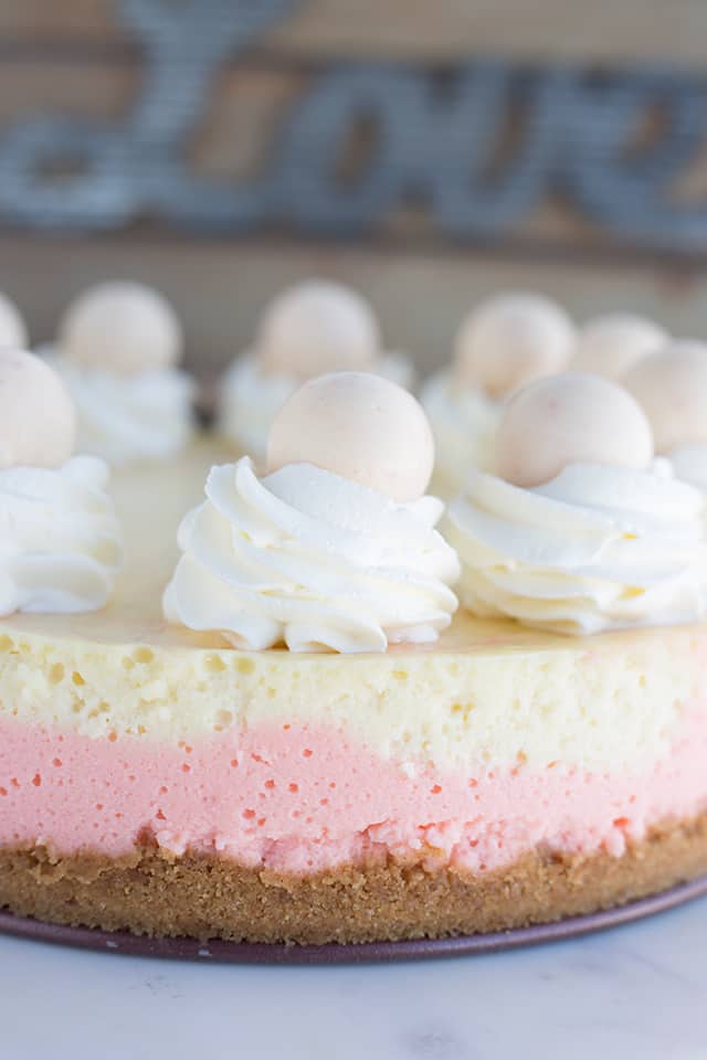 Full strawberries and cream cheesecake sitting on a marble cake stand