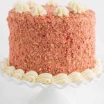 A red velvet cake with strawberry shortcake layers on a white cake stand.