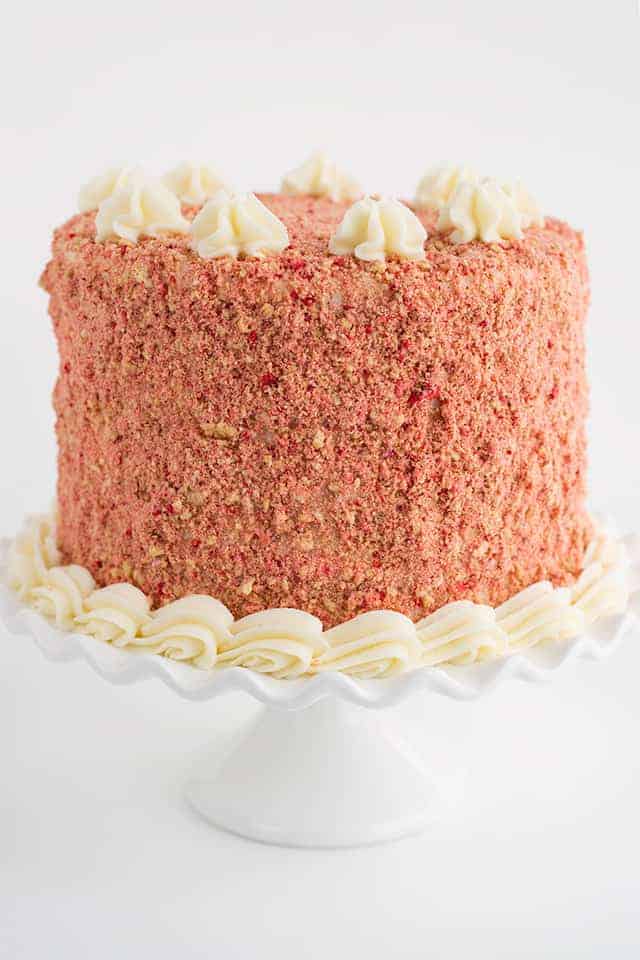 A red velvet cake with strawberry shortcake layers on a white cake stand.