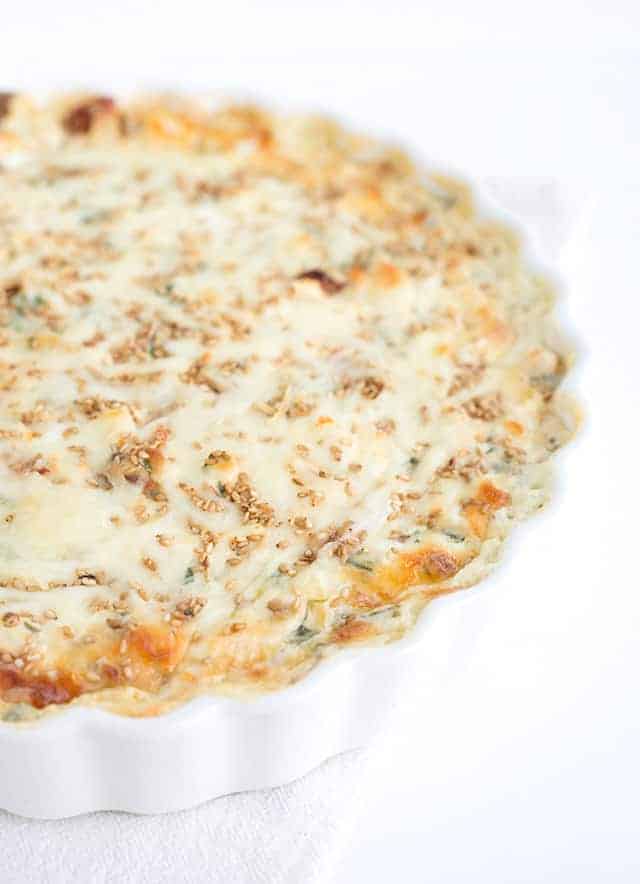 A white quiche with cheese and spinach.